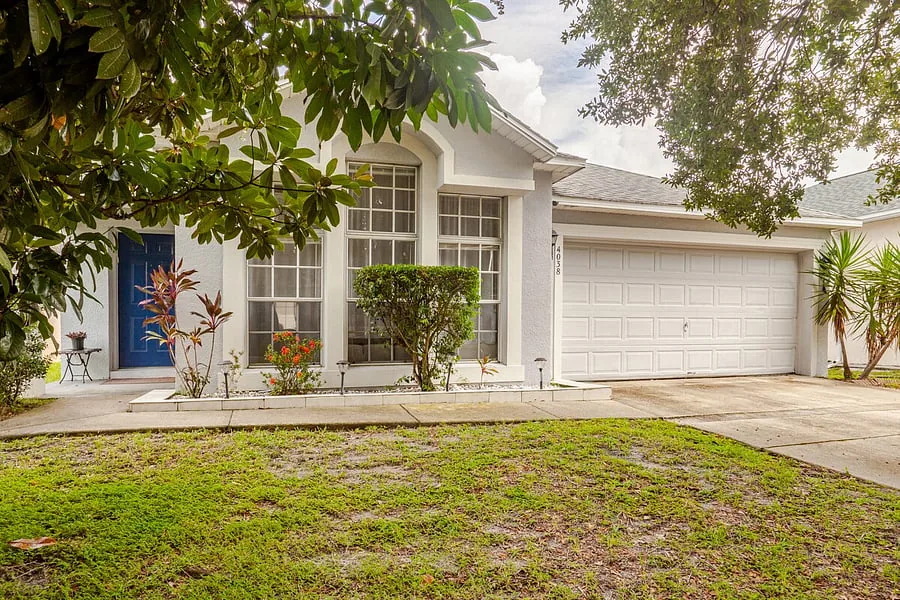 Front of the home with blue front door, lawn and two-car garage