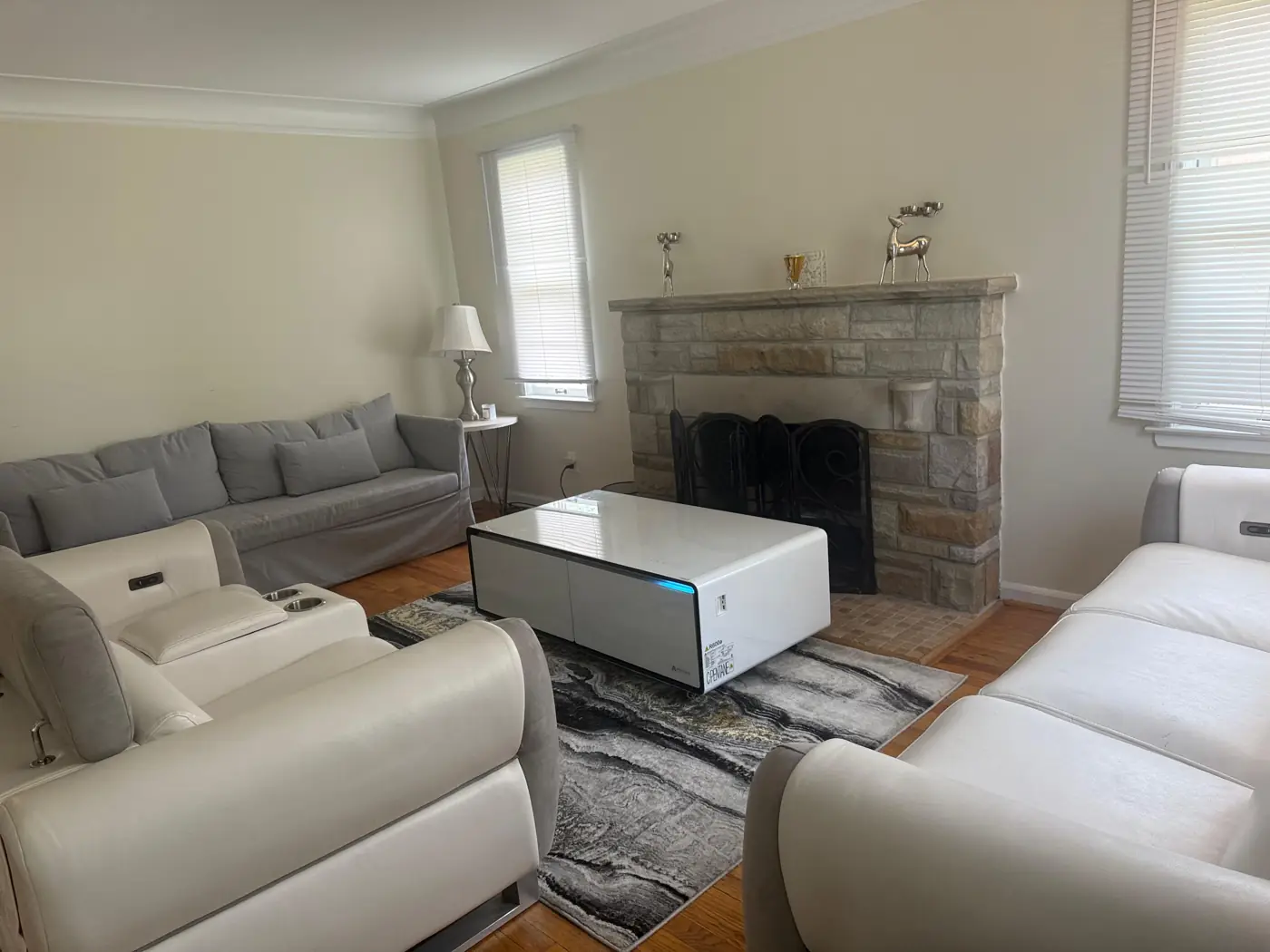 Furnished living room with white leather sectional and stone fireplace